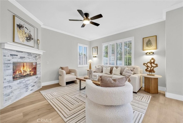 living room with a ceiling fan, baseboards, light wood-style floors, and crown molding