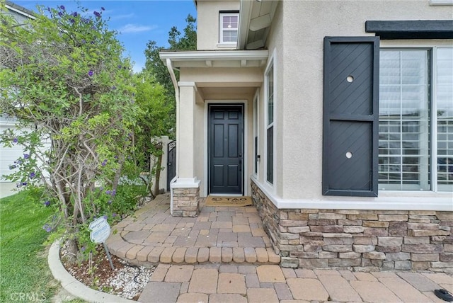 view of exterior entry featuring stucco siding and stone siding