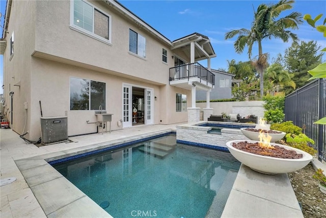 rear view of house featuring a patio area, a fenced in pool, a balcony, and stucco siding