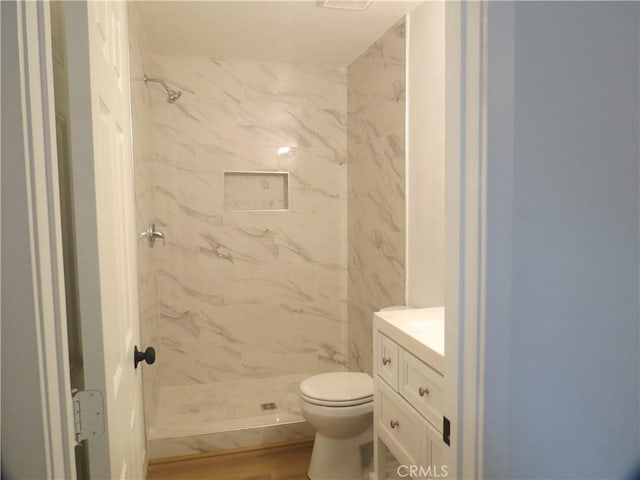 full bath with wood finished floors, a marble finish shower, vanity, and toilet