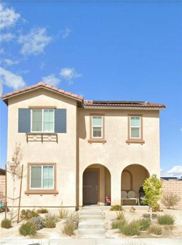 rear view of house featuring a tile roof and stucco siding