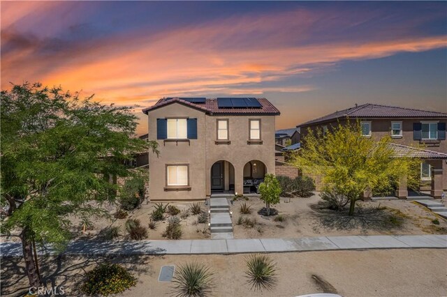 67410 Rio Vista Dr, Cathedral City, CA 92234 - view of front of home featuring roof mounted solar panels, stucco siding, a tiled roof, a porch, and stairs