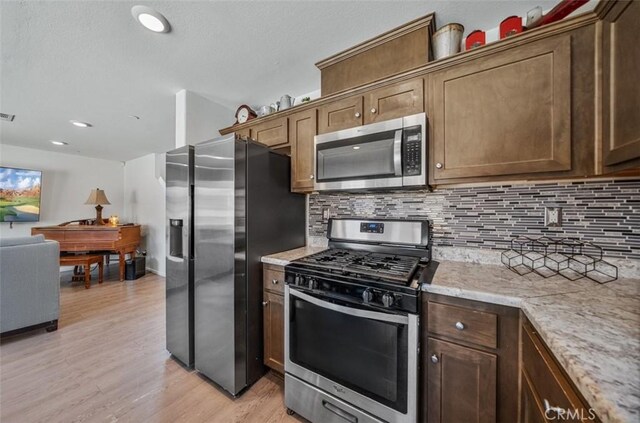 67410 Rio Vista Dr, Cathedral City, CA 92234 - kitchen featuring stainless steel appliances, decorative backsplash, light wood-style flooring, light stone countertops, and a textured ceiling