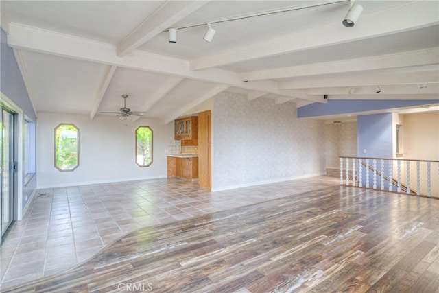 unfurnished living room featuring lofted ceiling with beams, baseboards, a ceiling fan, tile patterned flooring, and rail lighting