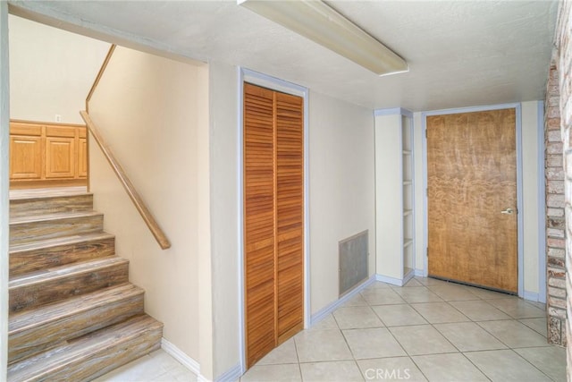 stairway featuring baseboards, tile patterned flooring, and visible vents