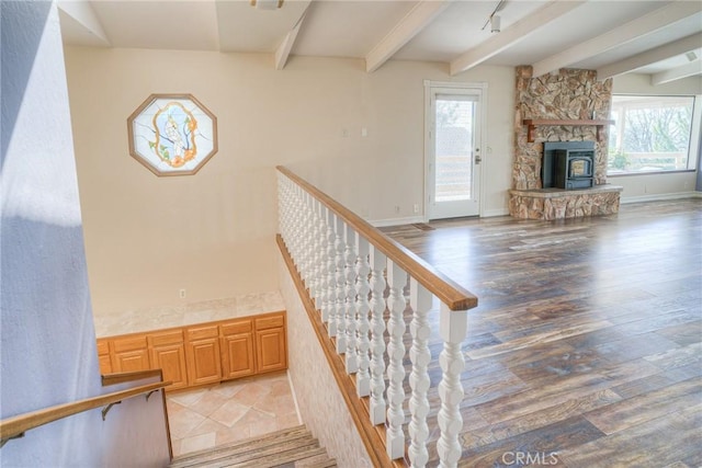 staircase featuring wood finished floors, beam ceiling, and a fireplace