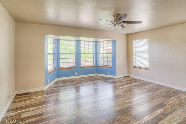 spare room featuring ceiling fan, baseboards, a healthy amount of sunlight, and wood finished floors