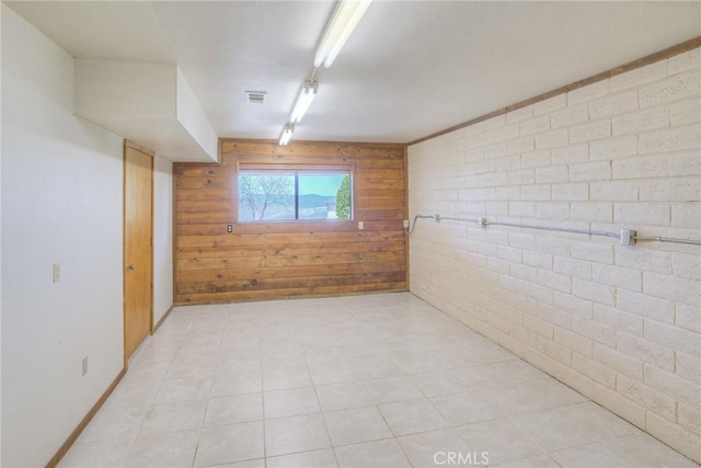 basement featuring wooden walls, visible vents, and track lighting