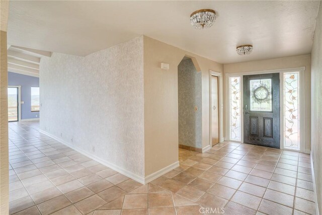 entrance foyer featuring plenty of natural light, baseboards, arched walkways, and light tile patterned floors