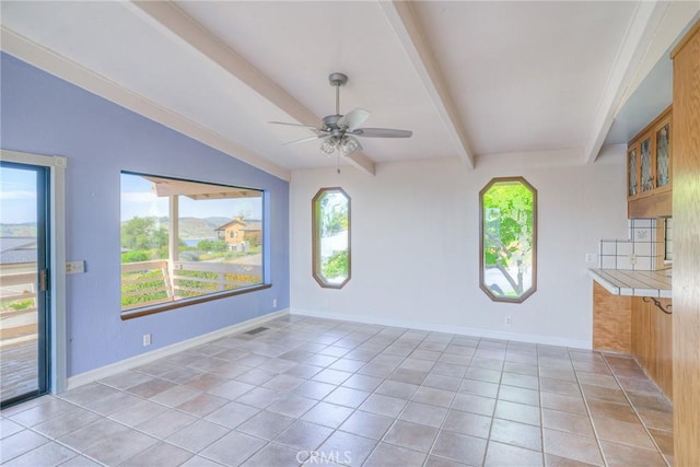 interior space with beam ceiling, a ceiling fan, baseboards, and light tile patterned floors