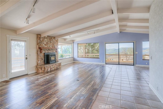 unfurnished living room with wood finished floors, rail lighting, vaulted ceiling with beams, and baseboards