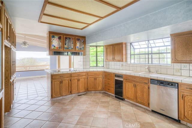 kitchen featuring decorative backsplash, dishwasher, a sink, and brown cabinetry