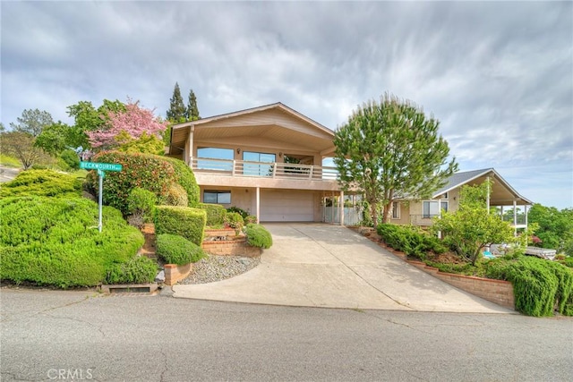 view of front facade with a garage, a balcony, and concrete driveway