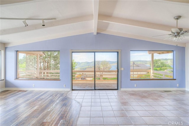 unfurnished living room with a healthy amount of sunlight, vaulted ceiling with beams, and ceiling fan