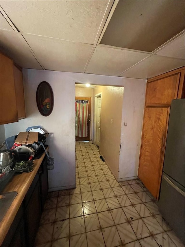 kitchen featuring light floors, freestanding refrigerator, and brown cabinetry
