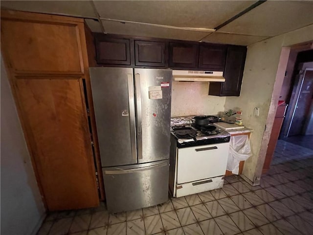 kitchen featuring light tile patterned floors, freestanding refrigerator, under cabinet range hood, and gas range oven