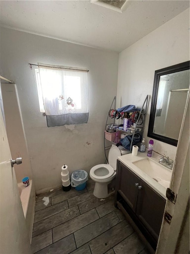full bathroom with vanity, wood finish floors, toilet, and visible vents