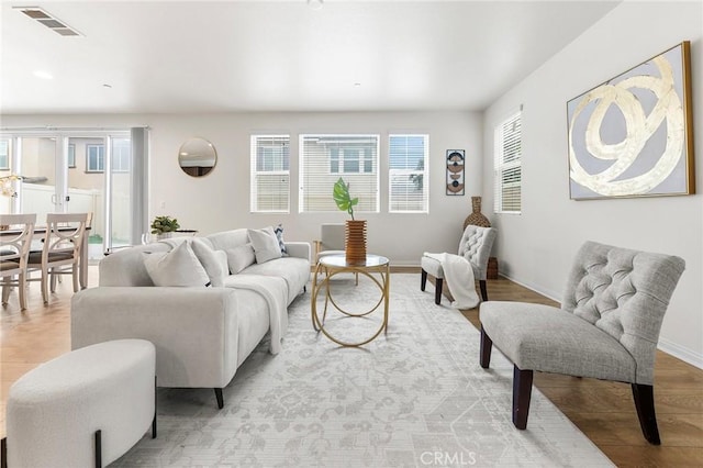 living room with visible vents, light wood finished floors, and baseboards
