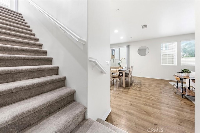staircase featuring recessed lighting, baseboards, visible vents, and wood finished floors