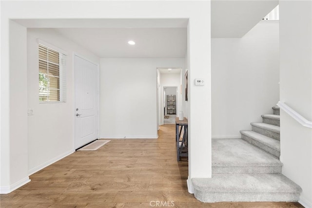 foyer featuring recessed lighting, baseboards, wood finished floors, and stairway