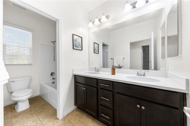 bathroom featuring double vanity, toilet, a sink, and tile patterned flooring