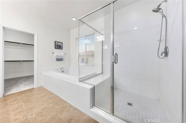 bathroom with tile patterned flooring, a bath, a stall shower, and a spacious closet