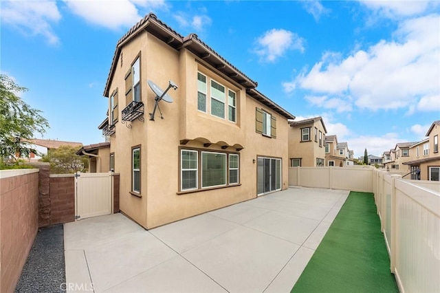 back of house with a fenced backyard, a patio, stucco siding, and a residential view