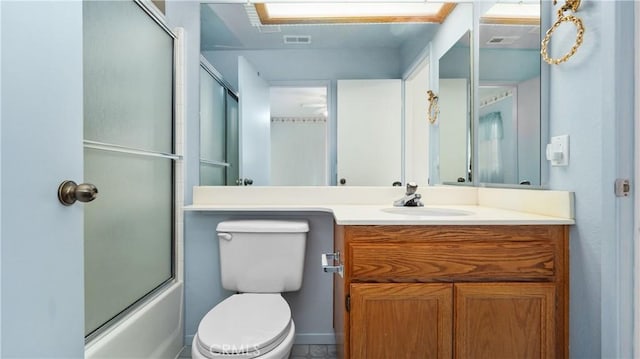 bathroom featuring visible vents, enclosed tub / shower combo, vanity, and toilet