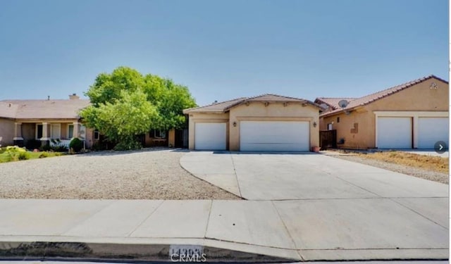 ranch-style house featuring a tile roof, an attached garage, concrete driveway, and stucco siding