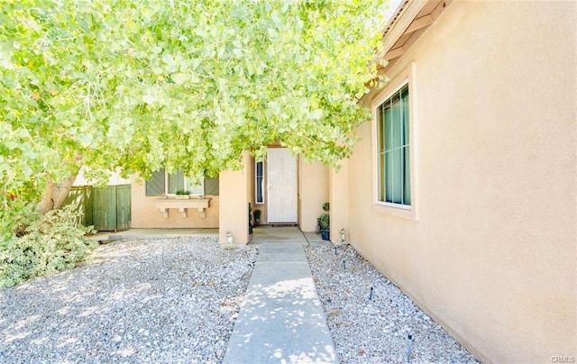 property entrance with stucco siding and fence