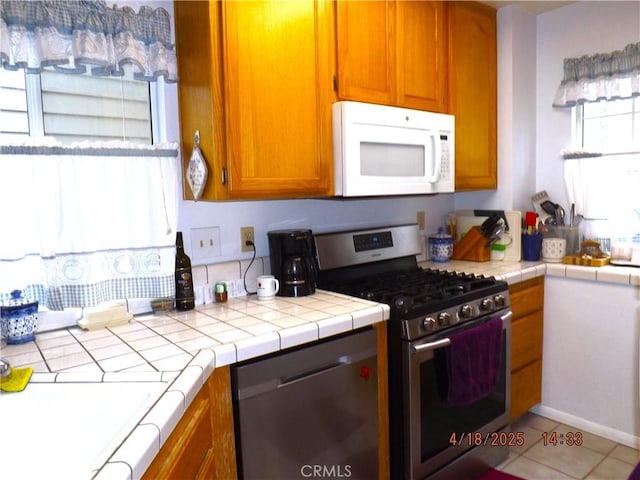 848 Oakmont, Lake Arrowhead, CA 92352 - kitchen with stainless steel appliances, brown cabinets, tile counters, and light tile patterned flooring