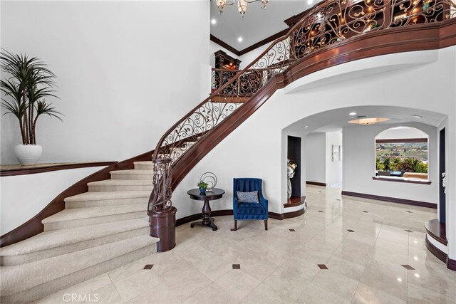 6 Riverstone, Laguna Niguel, CA 92677 - foyer entrance featuring arched walkways, a towering ceiling, baseboards, a chandelier, and stairway