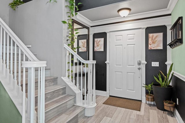 entrance foyer with baseboards, ornamental molding, stairs, and light wood-type flooring