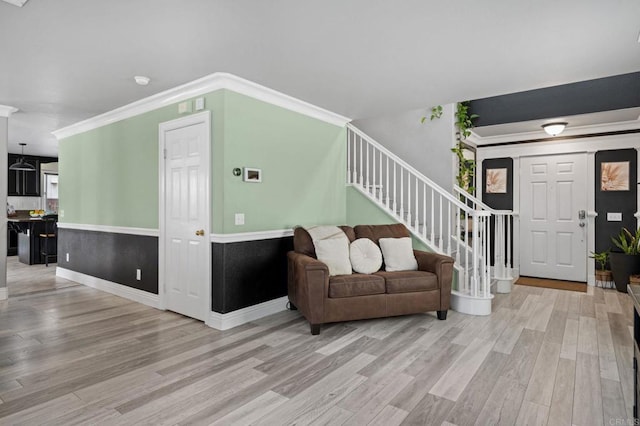 living area featuring baseboards, wood finished floors, stairs, and crown molding