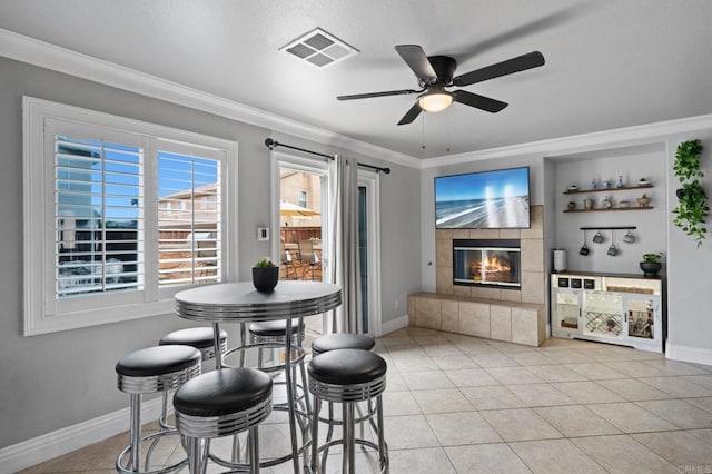 dining space with visible vents, crown molding, baseboards, a fireplace, and ceiling fan