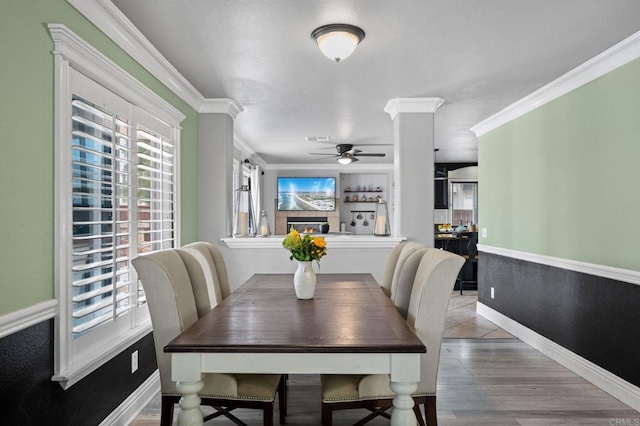 dining space featuring a ceiling fan, wood finished floors, baseboards, ornamental molding, and visible vents