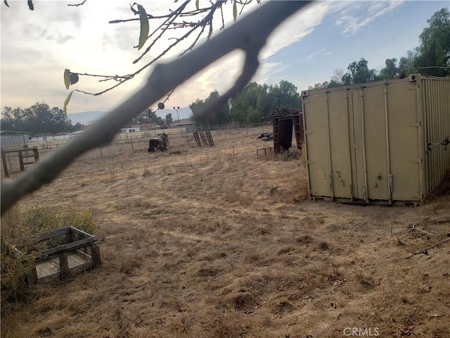 view of yard with fence and a rural view