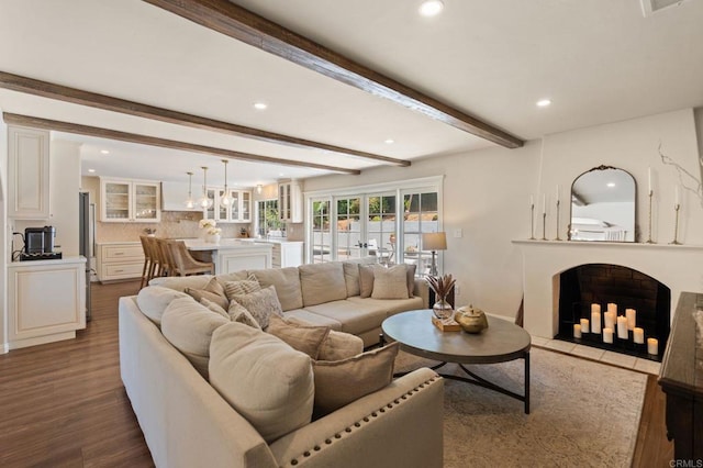 living room featuring beam ceiling, recessed lighting, wood finished floors, and a fireplace with flush hearth