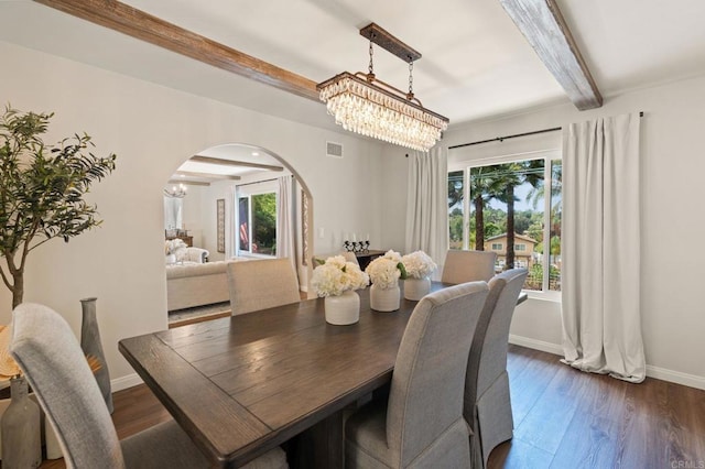 dining space featuring arched walkways, a notable chandelier, beam ceiling, and dark wood finished floors