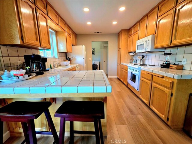 47180 Lookout Mountain Dr, Coarsegold, CA 93614 - kitchen featuring white appliances, tile countertops, tasteful backsplash, a peninsula, and light wood-type flooring