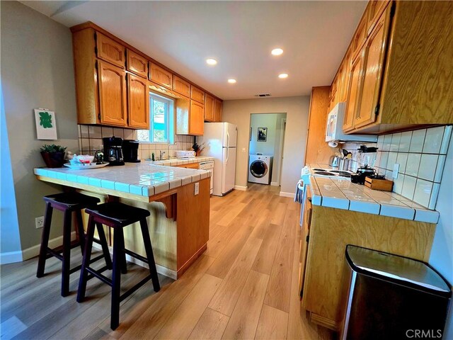 47180 Lookout Mountain Dr, Coarsegold, CA 93614 - kitchen featuring tile counters, washer / dryer, white appliances, a peninsula, and recessed lighting