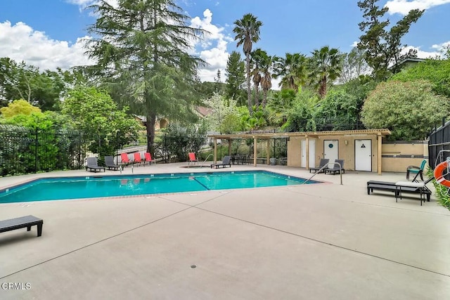community pool with fence, a patio, and view of scattered trees