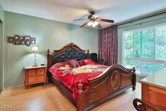 bedroom featuring light wood-style flooring, a textured ceiling, ceiling fan, and baseboards