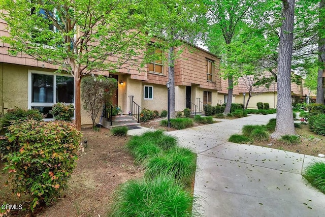 multi unit property featuring stucco siding and mansard roof