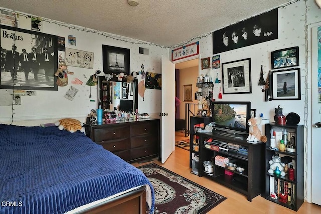 bedroom with a textured ceiling and wood finished floors