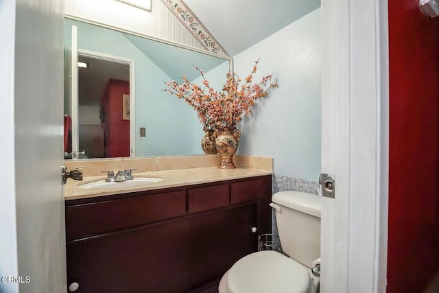 half bathroom with toilet, vanity, and vaulted ceiling