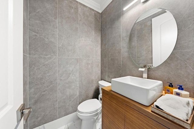 half bath with tile walls, vanity, crown molding, and toilet
