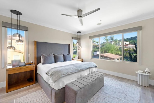 bedroom with baseboards, crown molding, and light wood-style floors