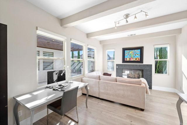 living area with light wood-type flooring, beamed ceiling, a premium fireplace, baseboards, and visible vents