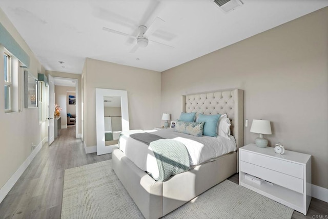 bedroom with baseboards, a ceiling fan, wood finished floors, and visible vents